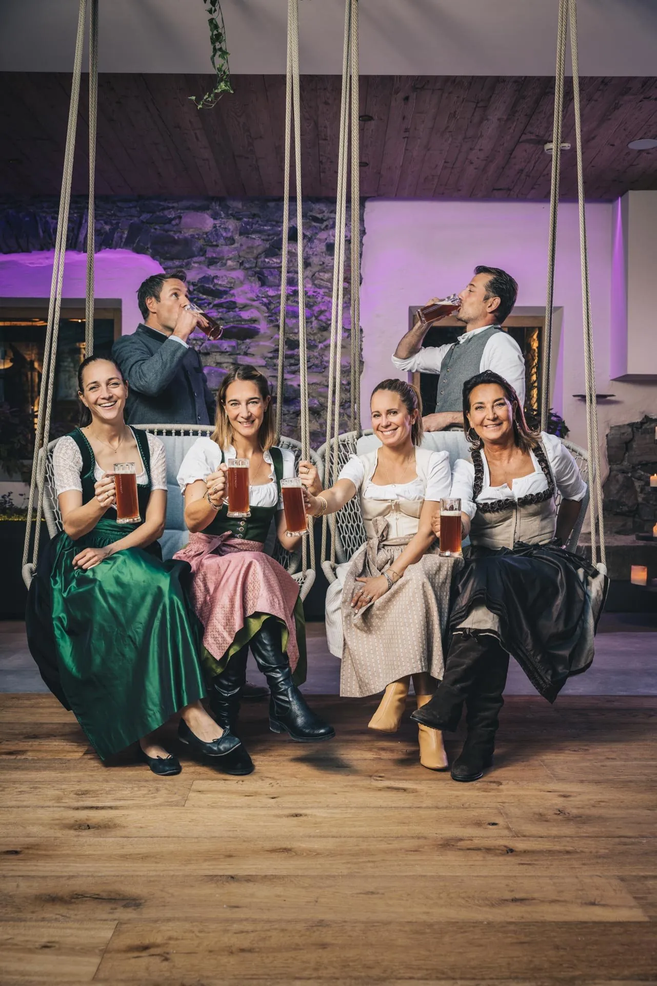 Team in Tracht auf Schaukeln mit Bier, Hotel Klosterbräu